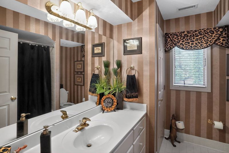 Bathroom with striped wallpaper, single vanity and shower