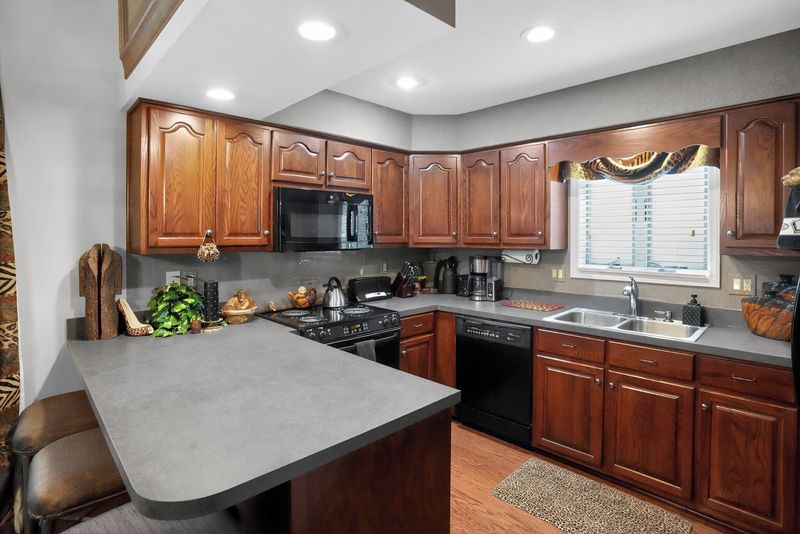 Fully equipped kitchen with wood cabinets, peninsula counter, dishwasher and range