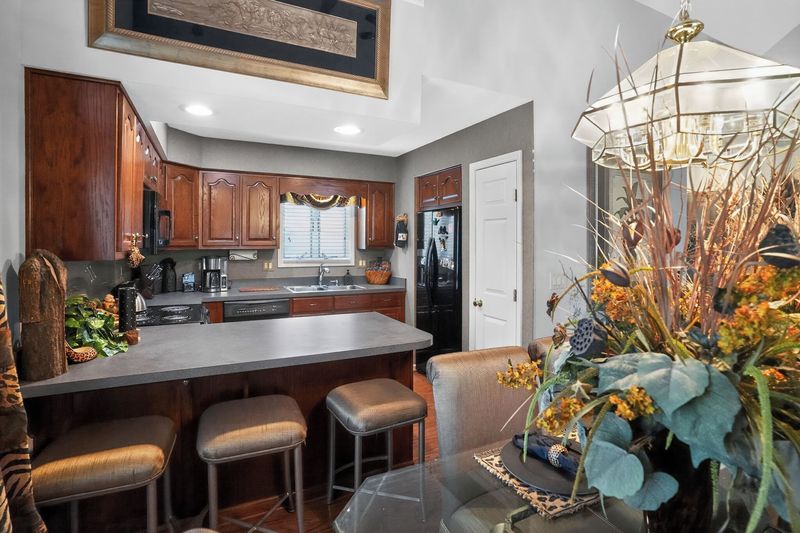 Kitchen breakfast bar with stools, wood cabinets and the dining area beyond