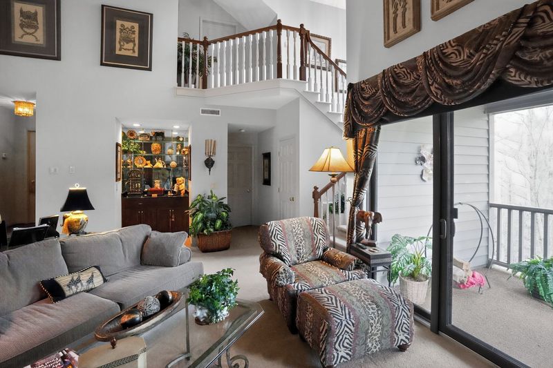 Living room with sliding glass doors to the balcony, staircase and loft railing above